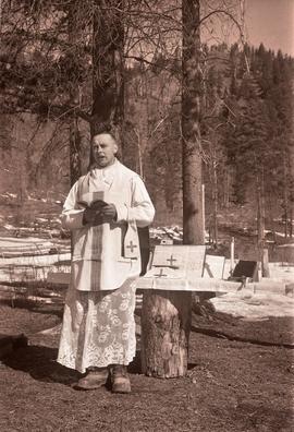 Military chaplain reading by a makeshift tree stump altar