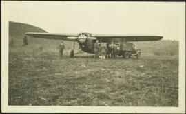 Men Standing by Airplane in Field