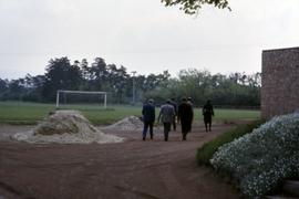 Iona Campagnolo walking toward a sports field with five unknown men in Germany