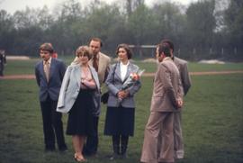 Iona Campagnolo holding flowers and standing with unknown people in a sports field in East Germany