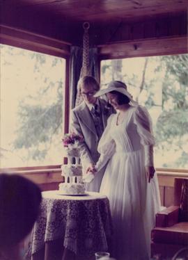 Newly married couple cutting wedding cake at reception