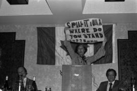 Iona Campagnolo holding up a sign stating "Spill it Iona Where do you stand? Hmmm . . . "