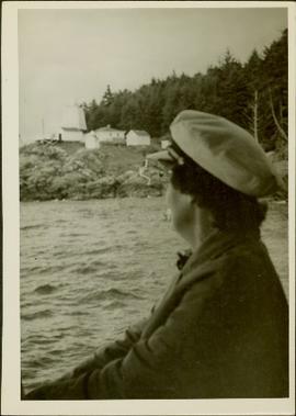 Woman seated in a boat looking at a lighthouse