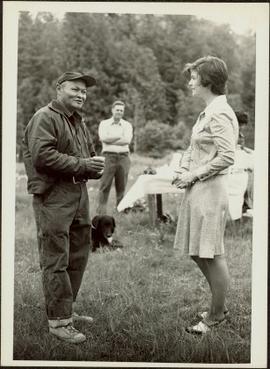 Iona  Campagnolo talking to an unidentified man outside while another man and a dog look on