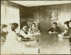 Iona Campagnolo sits at a board table with four unidentified men, Teresa Wright, and an unidentified woman