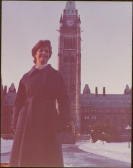 M.P. Iona Campagnolo posing in front of Parliament buildings in Ottawa, winter 1976
