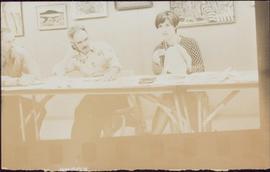 Iona Campagnolo speaking at long table as two men listen to her right, 1976