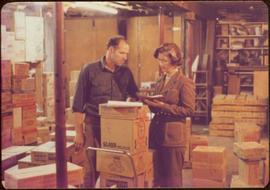 Minister Iona Campagnolo discusses freight costs with storekeeper Werner Funk, Queen Charlotte City, August 1977