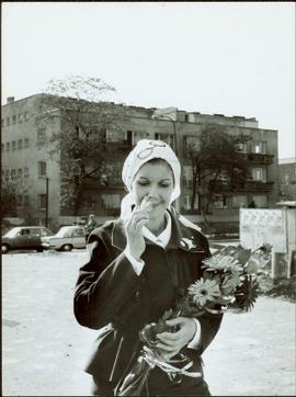 Minister Iona Campagnolo wearing an Olympic scarf around her head and smelling a bouquet of flowers, East Berlin