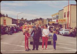 Mayor Peter Lester, Iona Campagnolo, and two unidentified children stand at the front of a Dominion Day parade in Prince Rupert, BC