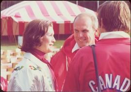 Commonwealth Games, Edmonton 1978 - Iona Campagnolo wears fringed white leather jacket while speaking with two unidentified men in red coats