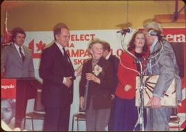 Prime Minister Pierre Trudeau, Iona Campagnolo, three unidentified men, and an unidentified woman stand on a stage at Campaign opener in Smithers, BC