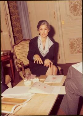 Paris Press Conference - Iona Campagnolo gestures while talking from chair at coffee table covered with documents