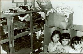 CUSO Mission, North-eastern Thailand - Unidentified children sit in front of shelves of clothing