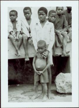 CUSO Mission in Waku-Kungo, Angola - Seven unidentified male children sit on a wall and stand in ...