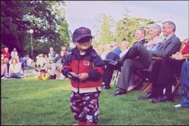 Lieutenant Governor Iona Campagnolo and crowd smile from lawn chairs, unidentified child in foreg...