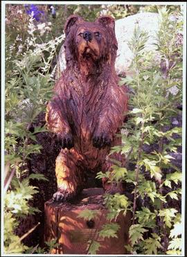 Chainsaw carving of a bear set among flowers in Terrace Gardens at Government House, Victoria, B.C.
