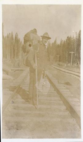 Surveyor with pack on railroad tracks