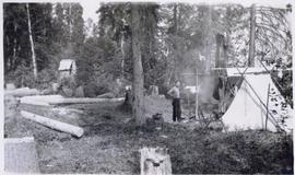 Man in campsite with tents and outhouse