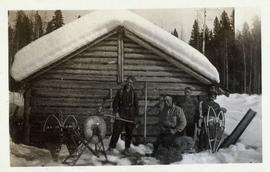 Four men standing in front of a cabin