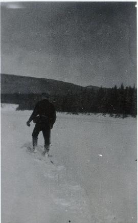 A man traipsing through the snow on snow shoes