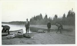 Canoes being turned over on shore by several men