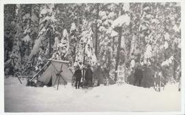 Four men at campsite with snowshoes and sleds