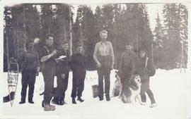 Group of men and their dogs standing in the snow