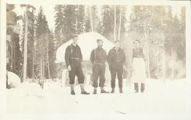 Four men standing in front of a log building