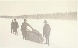 Four men hauling a sled laden with gear