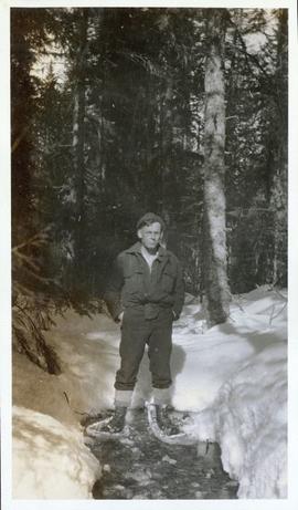 Man with snowshoes standing on a frozen creek