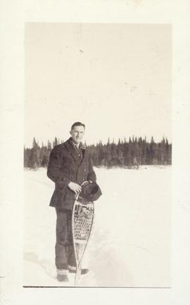 A man standing with his snow shoes in front of him