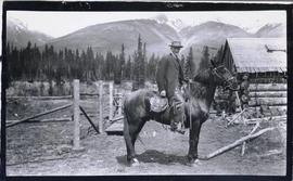 Horse and rider in front of a log building