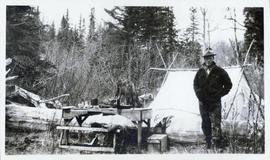 Man standing next to a picnic table in front of a tent