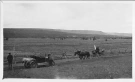 Horses pulling a wagon as it approaches a man with an automobile