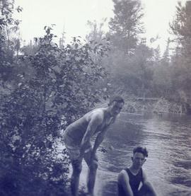 Two men about to go swimming in a river