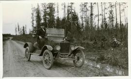 Man driving an automobile on a dirt road