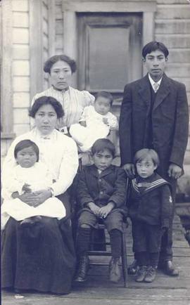 First Nations family - two older girls, both holding children, two younger boys and one older boy