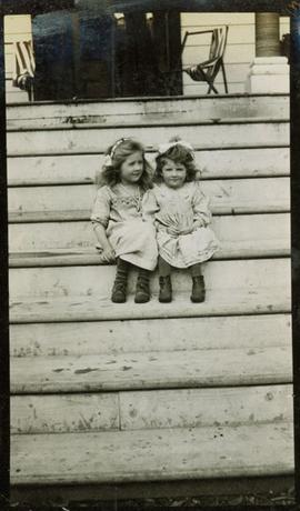 Two girls sitting on the front steps of a house