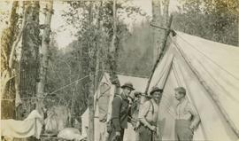 Three men outside of a large tent