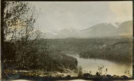 Landscape shot - Trees in the foreground, a river in the midground and mountains in the background