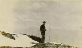Forest surveyor Parker Bonney on rocky outcropping with surveying tool