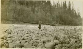 A man standing on a rock-strewn riverbank