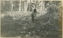 Hiker with pack traversing a muddy field