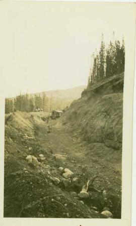 Shovel digging a ditch into a hillside