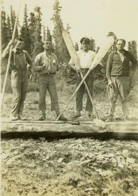 Thorne, J.R.M., Fred, Skookum standing on an overturned canoe