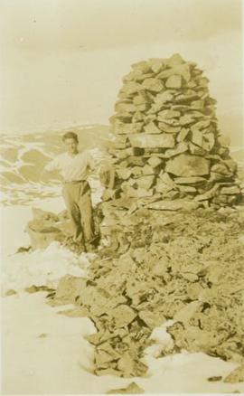 Fred, the cook, standing beside a mountain top surveying station