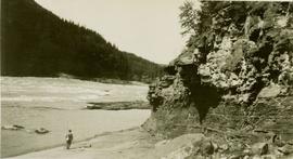 Man standing on river shore beside the Rocky Mountain Canyon