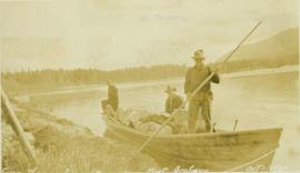 Three members of the survey crew on a loaded boat situated next to the shore