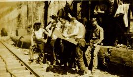 Workmen standing at the edge of a railway track reading a map